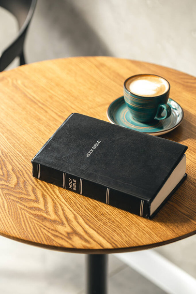Bir fincan kahve ve ahşap bir masada İncil, yakın plan, Hristiyanlık kavramı, Tanrı 'ya olan inanç.. - Fotoğraf, Görsel