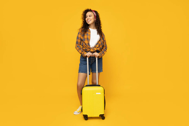 Jeune femme avec valise sur fond jaune - Photo, image