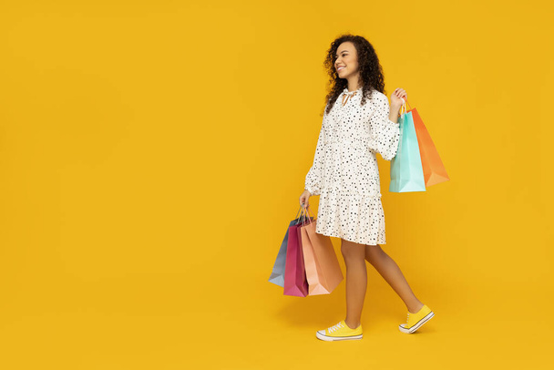 Young woman with shop bags on yellow background - Photo, Image