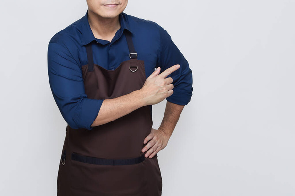 Asian Man wearing Apron in casual stylish clothing, standing upright pose with one hand pointing at something on the right, no face isolated white background - Valokuva, kuva