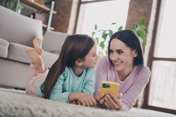 Photo of adorable cute mother daughter wear casual outfits chatting apple samsung modern device indoors house room. - Foto, afbeelding