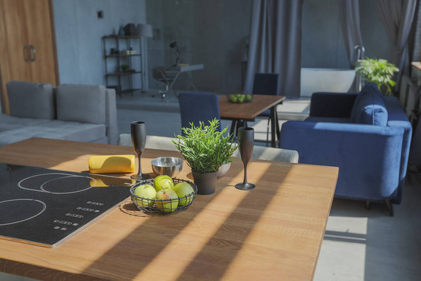 Modern minimalistic dark gray loft style studio apartment interior design. kitchen, sitting area, workplace, shower and bath. bright sun rays inside. - Фото, зображення