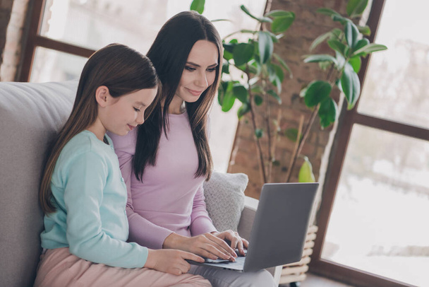 Photo of charming cute mother daughter wear casual outfits preparing homework modern gadget indoors house room. - Foto, afbeelding