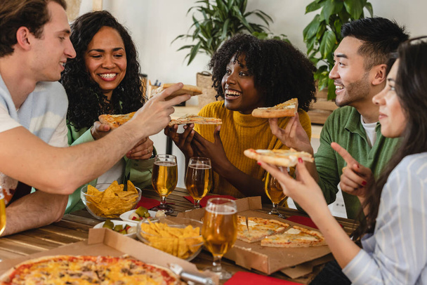 Amici multirazziali felici che mangiano pizza insieme a casa - amici felici pasto, consegna del cibo giovani che cenano in casa. - Foto, immagini