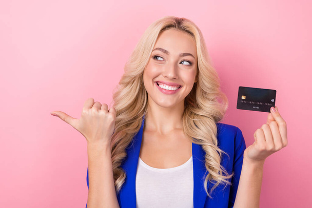 Portrait of charming cheerful person hand hold debit card look indicate finger empty space isolated on pink color background. - Φωτογραφία, εικόνα