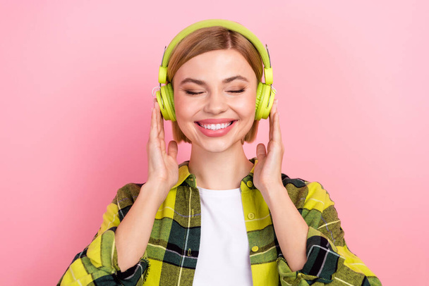 Photo of cute cheerful person closed eyes hands touch headphones isolated on pink color background. - Foto, imagen