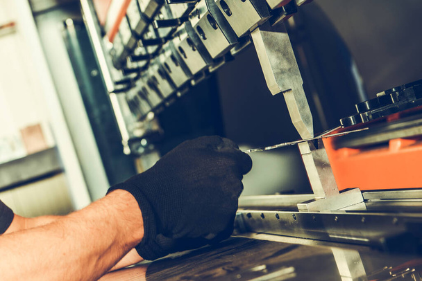 Fechar a mão do maquinista segurando um pedaço de metal sendo processado por máquina de dobra CNC. Indústria metalúrgica tema. - Foto, Imagem