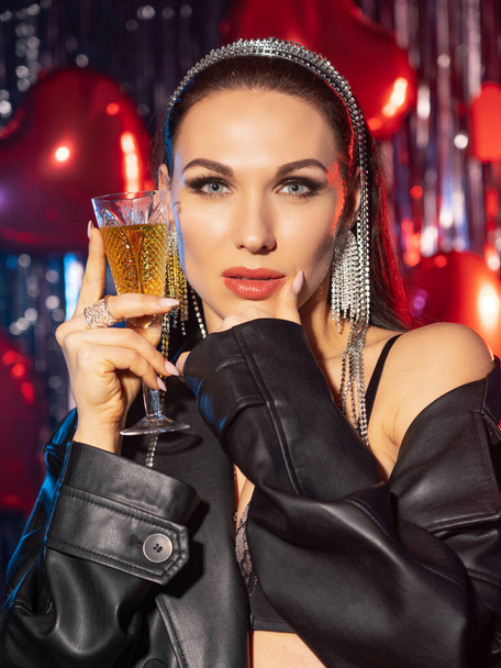 Beautiful, brunette with a glass of wine in her hands. She's in a leather coat and black sexy lingerie - Фото, зображення