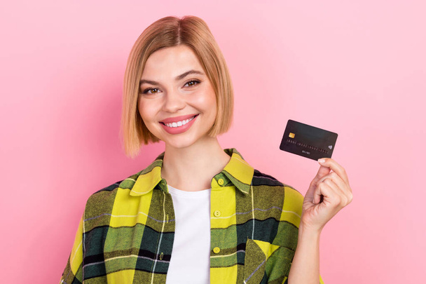 Retrato de encantadora chica positiva radiante brazo sonrisa celebrar tarjeta de débito de plástico aislado en el fondo de color rosa. - Foto, imagen