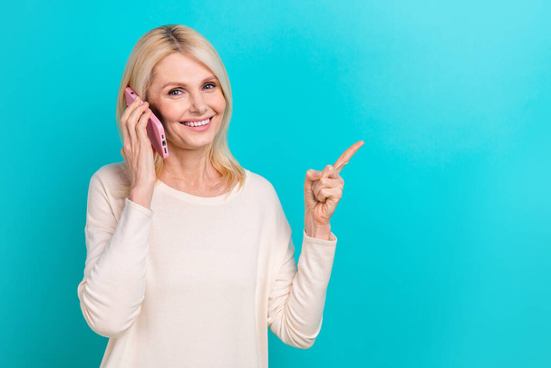 Photo of attractive smiling boss woman retired age phone calling indicate finger mockup commerce promo ad isolated on aquamarine color background. - 写真・画像