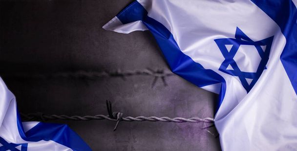 Jour du Souvenir de l'Holocauste. Yom HaShoah. Drapeau officiel d'Israël sur fond gris foncé en composition avec fil barbelé. Jour commémoratif pour le peuple juif. - Photo, image