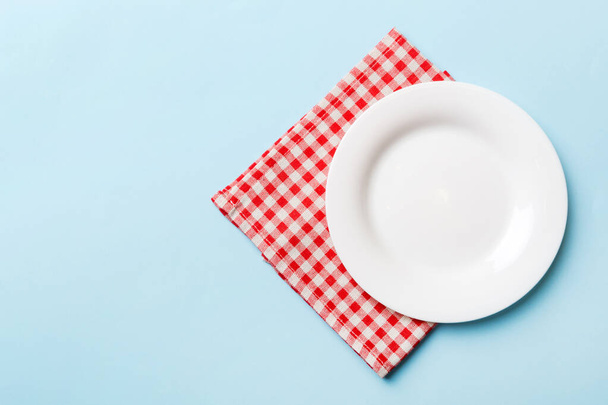 Top view on colored background empty round white plate on tablecloth for food. Empty dish on napkin with space for your design. - Photo, Image