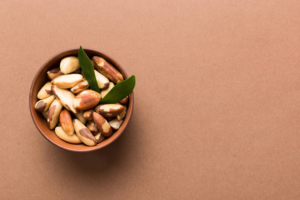 Fresh healthy Brazil nuts in bowl on colored table background. Top view Healthy eating bertholletia concept. Super foods. - Fotó, kép