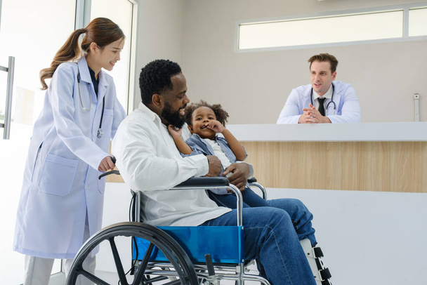 Les médecins examinent un patient noir qui a eu un accident avec une jambe cassée accompagné de sa femme et de son enfant. - Photo, image