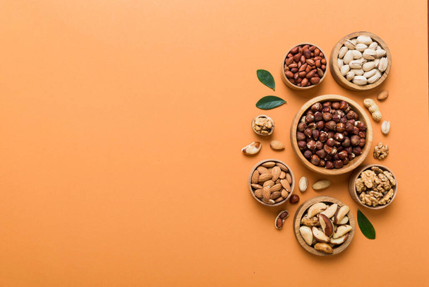 mixed nuts in wooden bowl. Mix of various nuts on colored background. pistachios, cashews, walnuts, hazelnuts, peanuts and brazil nuts. - Foto, imagen