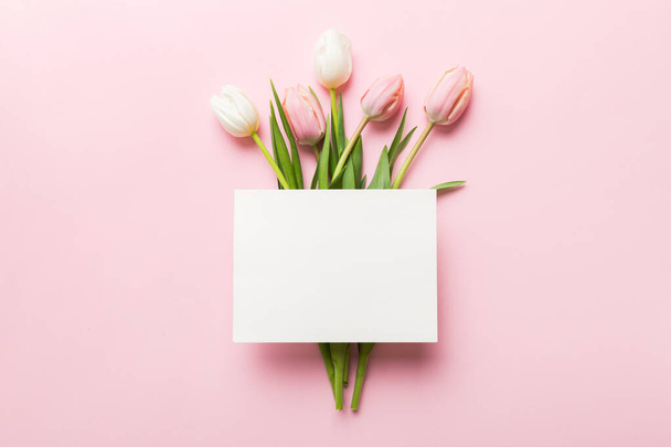 Composition with blank card and beautiful flowers tulip on coloredbackground. top view with space for you desing. - Fotó, kép