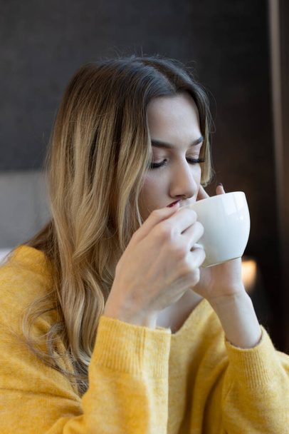 Beautiful young woman with closed eyes drinking tea - Foto, imagen