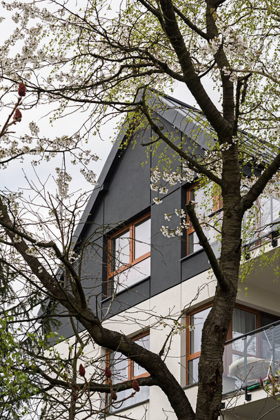 Détail pour façades et balcons dans un immeuble multifamilial moderne dans une ville européenne. Architecture intéressante. Parmi la végétation et les arbres. Printemps de floraison - Photo, image