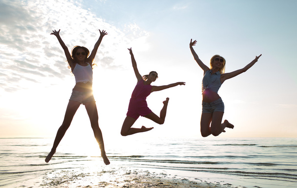 happy female friends dancing and jumping on beach - Photo, Image