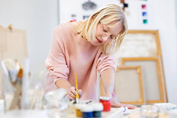 Young woman is in her painting studio - 写真・画像