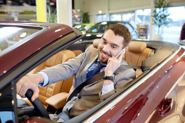 happy man sitting in car at auto show or salon - Фото, изображение