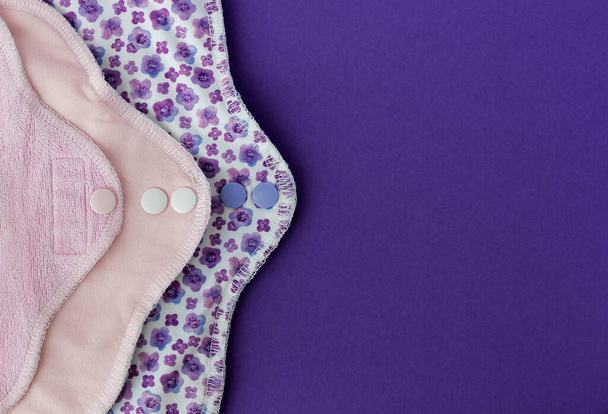 Бамбуковые гигиенические салфетки. Три цветных эко-многоразовых менструальных прокладки на фиолетовом фоне с копировальным пространством. Концепция женской гигиены, экологичные салфетки, нулевые запасы отходов - Фото, изображение
