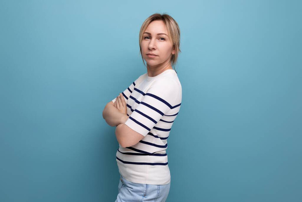 serious sullen blond girl clasped her hands together on a blue background with copyspace. - Foto, Bild