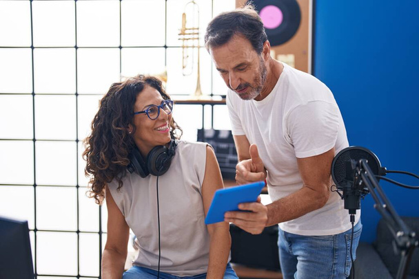 Мужчина и женщина-музыканты сочиняют песни с помощью компьютера и тачпада в музыкальной студии - Фото, изображение