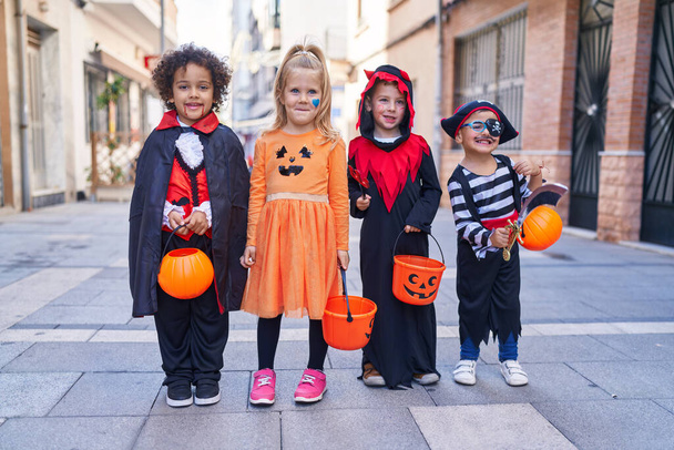 Cadılar Bayramı kostümü giymiş bir grup çocuk sokakta balkabağı sepeti tutuyor. - Fotoğraf, Görsel