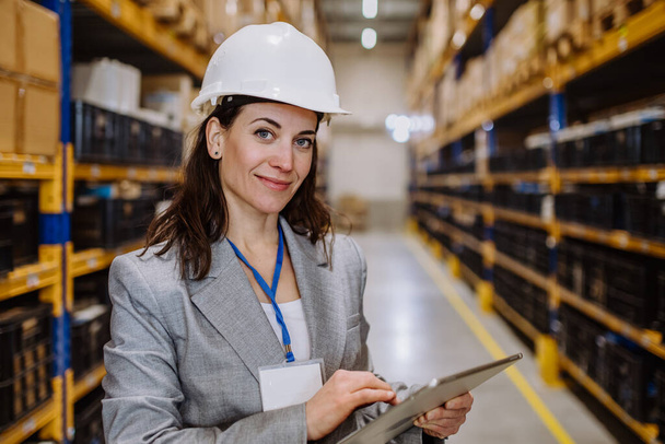 Manager woman in suit controlling goods in warehouse. - Foto, afbeelding