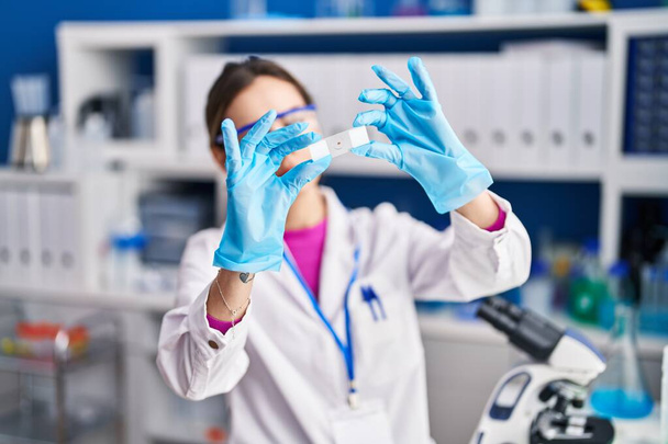 Młoda piękna latynoska kobieta naukowiec patrząc próbki w laboratorium - Zdjęcie, obraz