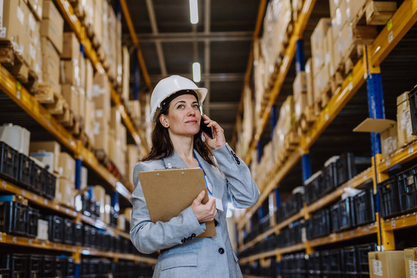 Manager woman in suit calling in warehouse. - Photo, Image