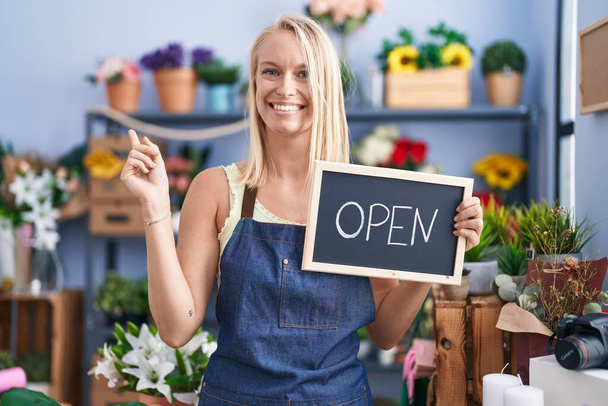 Young caucasian woman working at florist with open sign smiling happy pointing with hand and finger to the side  - Fotó, kép