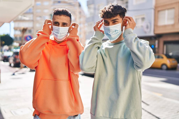 Two man couple wearing medical mask standing together at street - Photo, image