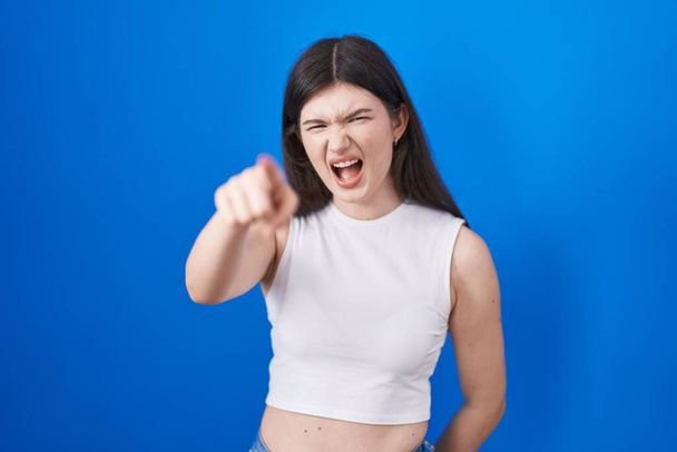 Young caucasian woman standing over blue background pointing displeased and frustrated to the camera, angry and furious with you  - Photo, Image