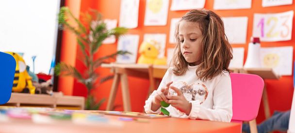Adorable hispanic girl playing with maths puzzle game sitting on table at kindergarten - Fotografie, Obrázek