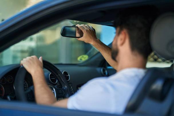 młody Latynos człowiek jazdy samochód dotykając widok z tyłu na ulicy - Zdjęcie, obraz
