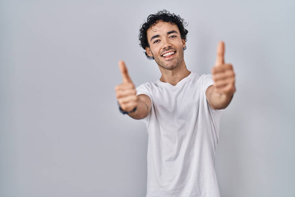 Латиноамериканець стоїть над відокремленим минулим, схвалюючи позитивний жест рукою, підносить усмішку і радіє за успіх. жест переможця.  - Фото, зображення