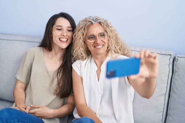 Two women mother and daughter make selfie by smartphone at home - Foto, Bild