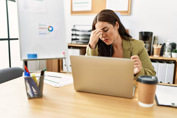 Giovane bella donna ispanica business worker stressato con il computer portatile in ufficio - Foto, immagini