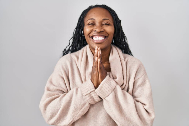 African woman standing over white background praying with hands together asking for forgiveness smiling confident.  - Photo, Image