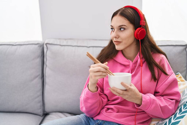 Молода жінка слухає музику, їсть китайську їжу вдома
 - Фото, зображення