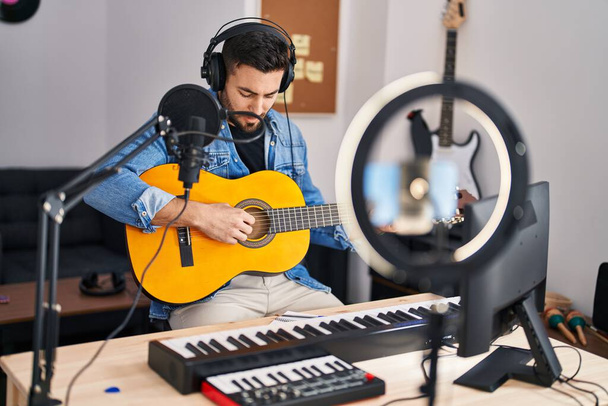 Young hispanic man musician having online guitar lesson at music studio - Photo, Image