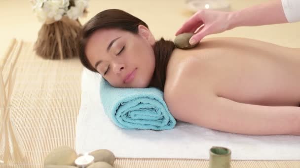 Mujer recibiendo masaje de espalda en el spa con piedras de lava
 - Imágenes, Vídeo