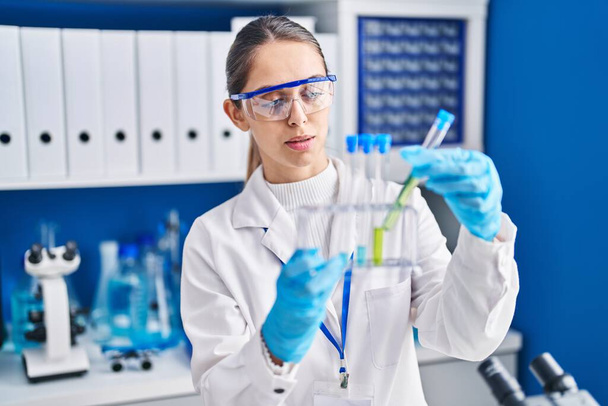 Νεαρή γυναίκα επιστήμονας που κρατά δοκιμαστικούς σωλήνες στο εργαστήριο - Φωτογραφία, εικόνα