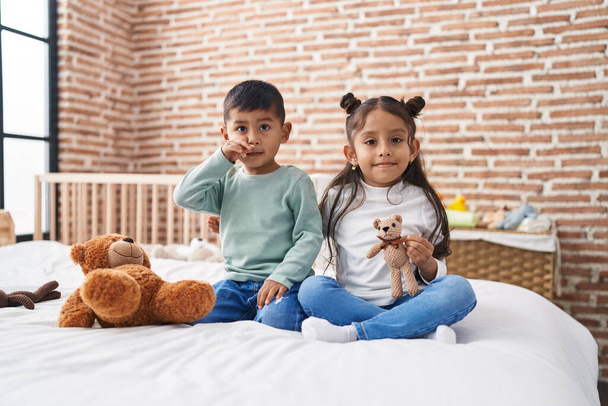 Liebenswerter Junge und Mädchen lächeln selbstbewusst und halten Teddybär im Schlafzimmer - Foto, Bild