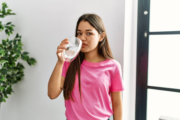 Jonge latijnse vrouw drinkwater thuis - Foto, afbeelding
