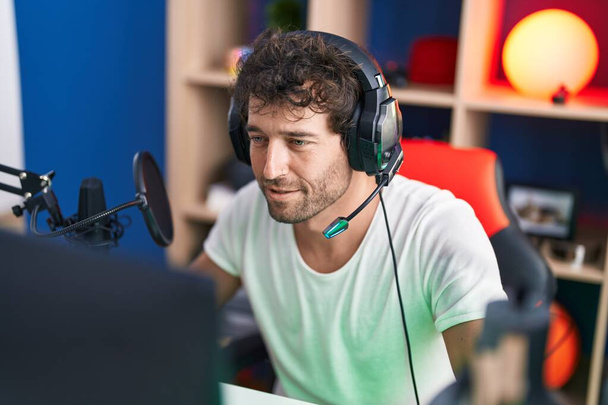 Jonge Latijns-Amerikaanse man streamer spelen video game met behulp van computer in de muziekstudio - Foto, afbeelding
