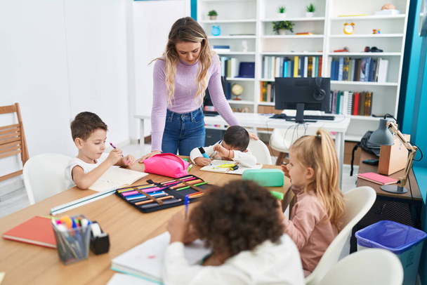 Kobieta i grupa dzieci mają lekcje siedzi na stole w klasie - Zdjęcie, obraz