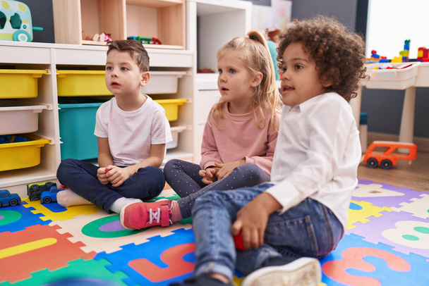 Grupa dzieci siedzących na podłodze z miłą ekspresją w przedszkolu - Zdjęcie, obraz